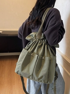 Minimalist olive green drawstring bucket bag with large pockets and shoulder strap