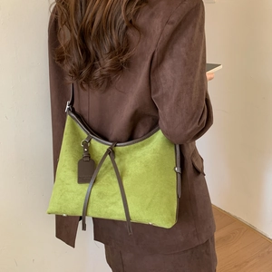 Detail of green suede tote bag with brown leather straps and metal rivets on base