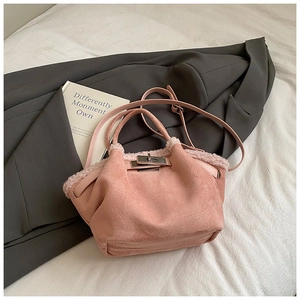 Close-up of pink suede bucket bag with fuzzy trim and metallic twist lock on blazer
