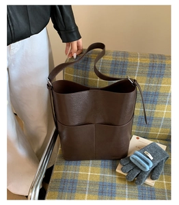 Gros plan du sac seau marron foncé montrant le grain fin et les détails de couture