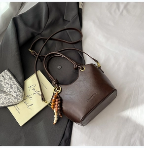 Detail of dark brown retro bucket bag with polished PU leather and wooden bead charm