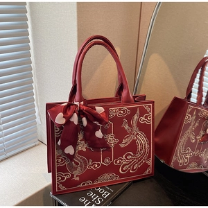 Close-up of red bridal handbag featuring golden dragon phoenix embroidery and Xi character