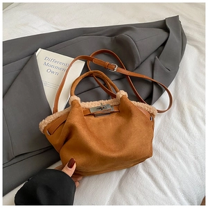 Brown suede bucket bag with beige faux fur trim and metal twist lock in cozy setting
