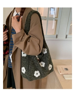 Detail showing deep green plush tote bag with white floral embroidery and drawstring design