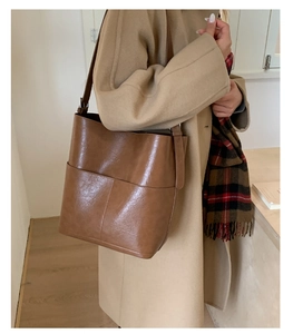 Vue détaillée du sac seau marron en cuir ciré avec deux grandes poches sur le devant