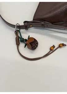 Détail d'un charm de sac en cuir en forme de rose avec perles en bois sur sac brun