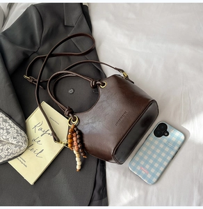 Detail of vintage dark brown bucket bag with wood bead tassel and embossed branding