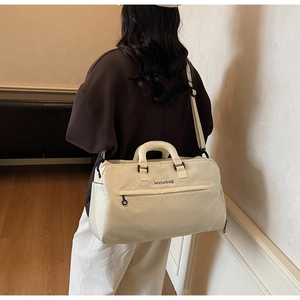 Detail der cremefarbenen Reisetasche mit verstärkten Griffen, Gurt und Logo-Stickerei