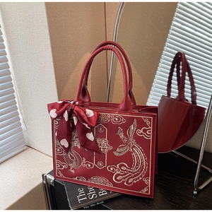 Macro detail of red bridal handbag with gold dragon phoenix embroidery and silk scarf wrap