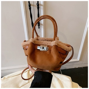 Detail of brown suede tote bag with white faux shearling trim and silver metal twist lock