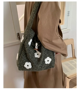 Detail of green plush tote bag featuring white floral embroidery and wooden horn buckle