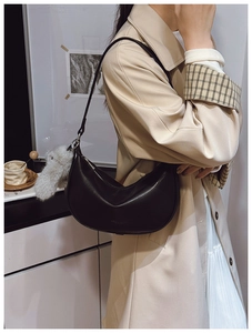 Close-up of black matte leather hobo bag with plush animal pendant and adjustable strap