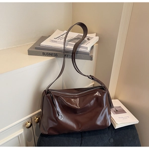 Macro detail of dark brown glossy leather tote showing smooth texture and silver zipper