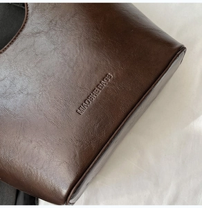 Close-up of litchi texture on dark brown leather bag with embossed MIAOSHE logo
