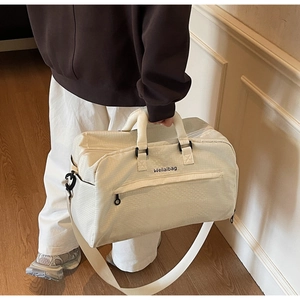 Detail der cremeweißen Reisetasche mit Nylon-Struktur und verstellbarem Schultergurt