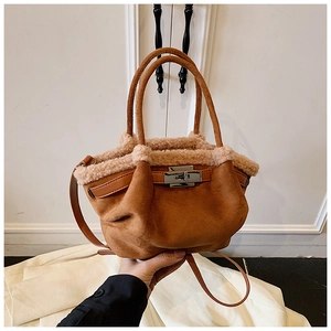 Detailed view of brown suede tote with faux shearling trim and silver metal twist lock