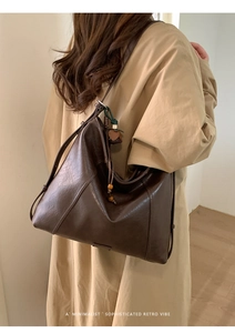 Détail du sac cabas en similicuir marron foncé avec pompon en bois et texture rétro