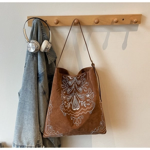 Detailansicht weißer böhmischer Stickerei auf einer braunen Wildledertasche im Hobo-Stil