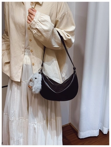 Detail of a black half-moon hobo bag featuring a cute grey plush rabbit charm accessory