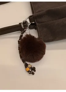 Detail of dark brown plush bag charm with braided rope and vintage metallic beads