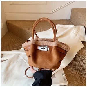 Close-up of brown suede handbag with white faux fur trim and silver twist lock detail