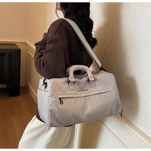 Detail der großen grau karierten Reisetasche mit Tragegurten und Reißverschlüssen