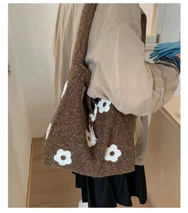 Close-up of brown plush tote bag with white flower embroidery and soft wool texture