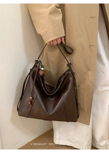 Détail du grand sac cabas marron avec cordons latéraux et pendentif floral élégant