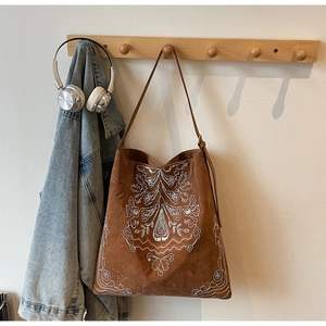 Detailaufnahme der weißen Boho-Stickerei auf einer großen braunen Wildleder-Tote-Bag
