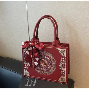 Close-up of red leather wedding tote bag with golden double happiness embroidery