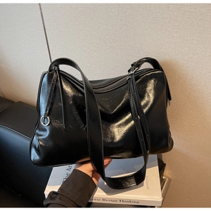 Detail of glossy black tote bag made from high-shine patent leather with silver ring hardware