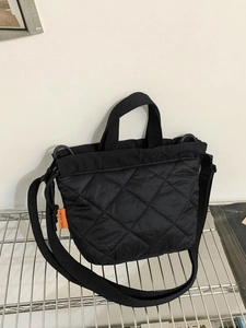 Borsa a secchiello in nylon trapuntato nero con motivo a rombi ed etichetta arancione