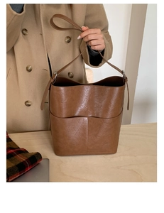 Vue détaillée du sac seau marron vintage avec poche avant et texture en cuir brillant