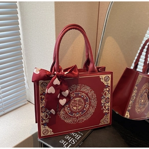 Detail of red wedding tote bag featuring golden dragon embroidery and festive bow