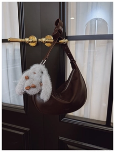 Detailed view of deep brown hobo bag with wide knotted strap and plush bunny charm