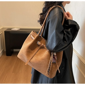 Detail of brown suede tote bag with silver buckle and woven tassel decoration