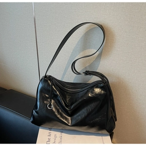 Detail of black glossy leather tote bag with soft texture and slim shoulder strap