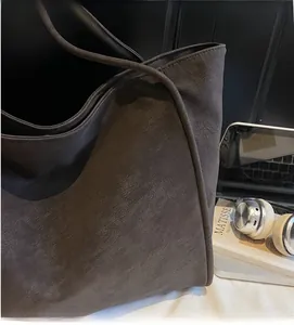 Detail of soft dark brown leather texture and stitching on a large commuter tote bag