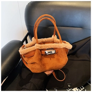 Detail view of brown suede tote bag with cream faux fur trim and silver twist-lock closure