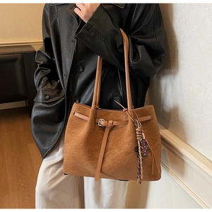 Detail of vintage brown suede tote bag featuring silver buckle and leopard bear charm