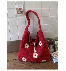 Detail of red knit tote bag featuring white floral embroidery and wooden toggle closure
