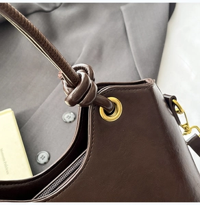 Macro view of dark brown leather bucket bag with gold grommet and knotted strap details