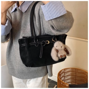 Detail of black tote bag with white contrast stitching and a cute bunny plush charm
