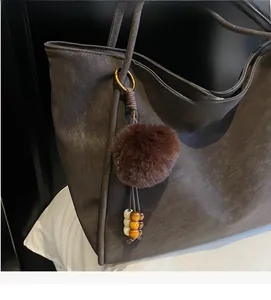 Close-up of vintage large tote bag with dark brown faux leather and pompom bead charm