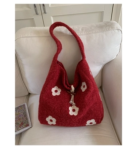 Detail of red plush tote bag with white flower embroidery and wooden buckle closure