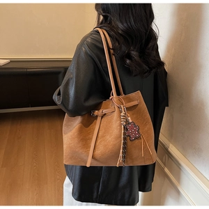 Macro detail of brown vintage tote bag showing matte texture and cute bear pendant charm