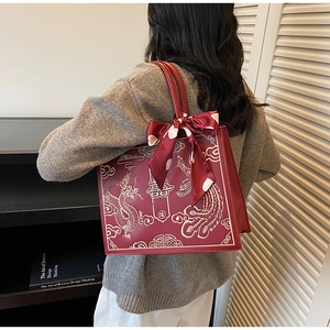Detail of red bridal tote featuring gold embroidery and a polka dot silk scarf handle