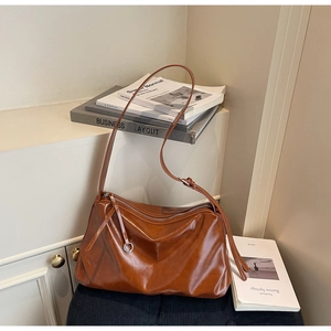 Detailed view of brown glossy leather tote bag with smooth texture and zipper detail