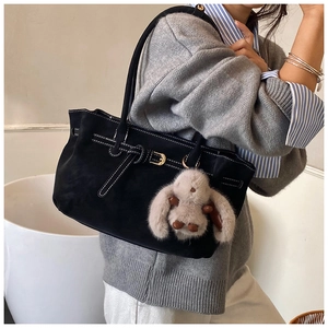 Detail of black suede tote bag featuring white contrast stitching and a plush rabbit charm