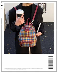 Detail of colorful plaid pattern backpack with red faux leather straps and double zippers
